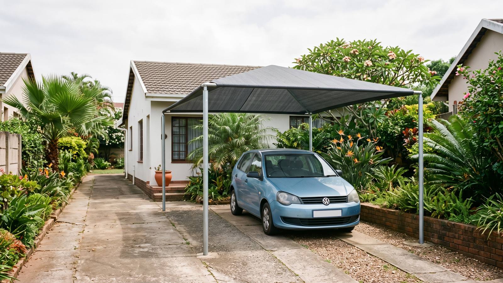 Single-bay shadeport with charcoal shade cloth over a hatchback in a narrow side driveway.